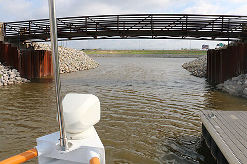 Pedestrian bridge stretching across Oklahoma River with dock to the right.