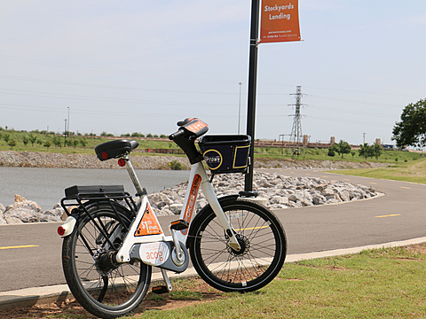 Spokies electric bike parked by flagpole at Stockyards Landing for Oklahoma River Cruises