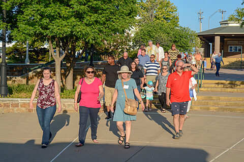 Large group of individuals walking towards landing to board a boat.
